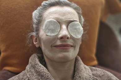 Frau bekommt im Wellnessbereich eine Gesichtsmaske