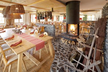 Gemütliches Restaurant mit Kamin und Holztischen im Hotel Oberstdorf Ob im rustikalen, stilvollen oder modernen Bereich im Restaurant des Hotel Oberstdorf, der offenen Kamin bildet den Mittelpunkt.