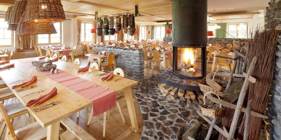 Gezellig restaurant met open haard en houten tafels in Hotel Oberstdorf. Of het nu gaat om het rustieke, stijlvolle of moderne gedeelte van het restaurant van Hotel Oberstdorf, de open haard vormt het middelpunt.