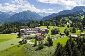 Außenansicht des Hotel Oberstdorfs im Sommer. Im Hintergrund sind die Allgäuer Alpen zu sehen.