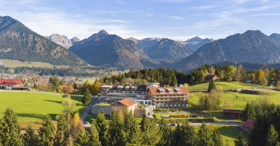 Außenaufnahme vom Hotel Oberstdorf im Herbst mit den Allgäuer Alpen als Hintergrund.