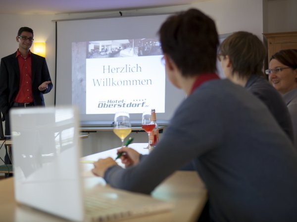 Präsentation vor Teilnehmern in einem Tagungsraum im Hotel Oberstdorf Im Hotel Oberstdorf haben die Teilnehmer die Möglichkeit für eine kreative Tagung in den Bergen. Während der Veranstaltung sorgt das Team vom Hotel Oberstdorf für die optimale Verpflegung. Das macht das Haus zu Ihrem Tagungshotel im Allgäu.