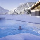 Beheizter Außenpool im Winter mit Blick auf die Allgäuer Berge im Hotel Oberstdorf Kein Angst, Sie müssen nicht in den Schnee treten, bevor sie das herrlich warme Wasser des Pools im Hotel Oberstdorf spüren können. Der Einstieg ins Wasser erfolgt bequem von Innen. Denn auch im Winterurlaub gehört ein Bad für uns dazu.