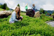 Kinder spielen während dem Familienurlaub in Oberstdorf auf der grünen Wiese vor dem Hotel. Im Hintergrund die Berge des Kleinwalsertals.