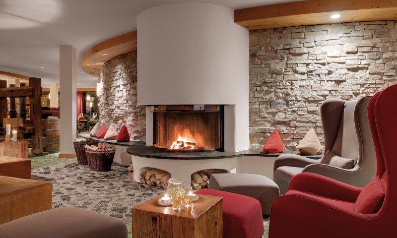 Große gemütliche Ohrensessel, ein knisterndes Kaminfeuer und erlesene Getränke finden Sie in der Lounge des Hotel Oberstdorf. Hier lassen sich entspannte Abende im Allgäu verbringen.