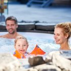 Familie mit Kind beim gemeinsamen Entspannen im beheizten Außenpool des Hotel Oberstdorf – Wellness und Familienzeit im Allgäu.