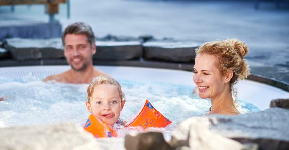 Familie mit Kind beim gemeinsamen Entspannen im beheizten Außenpool des Hotel Oberstdorf – Wellness und Familienzeit im Allgäu.