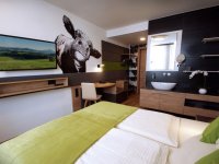 Das Zimmer hat ein Bett, einen Schreibtisch und eine Wandmalerei. Es gibt einen Fernseher und das Bad ist modern.