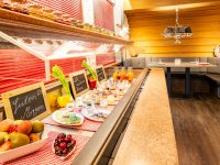 Ein Frühstücksbuffet zeigt verschiedene Speisen und Getränke in einem Restaurant am Morgen. Gäste können auswählen.