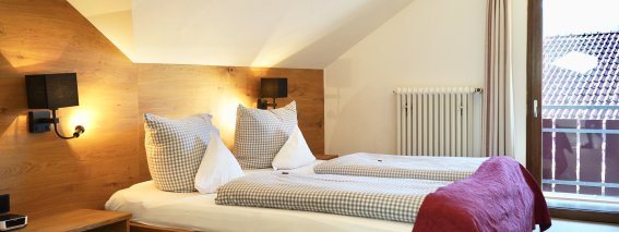 Das Zimmer hat zwei Betten und einen Balkon mit Blick nach draußen. Es ist hell und freundlich gestaltet.