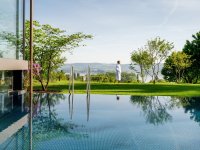 Hotel Hirschen Horn Pool. Pool mit Ausblick auf grünen Rasen und eine Frau im weißen Bademantel