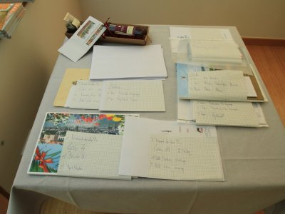 Auf einem Tisch liegen verschiedene Papiere und Postkarten mit handgeschriebenen Adressen.