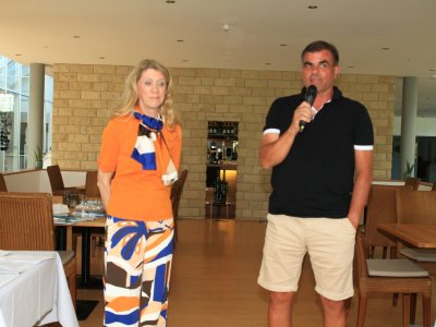 Zwei Personen stehen in einem Restaurant und sprechen zu den Gästen. Eine Person hält ein Mikrofon und erklärt etwas.