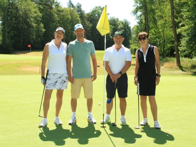 Vier Golfer stehen auf dem Grün und posieren für ein Bild. Es ist ein sonniger Tag im Golfclub.