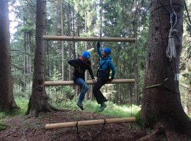 In unserem Wald-Seilgarten am Allgäuer Berghof eine wackelnde Leiter bezwingen, indem man seine eigene Balance und Stabilität sichert und gleichzeitig seinem Team hilft.