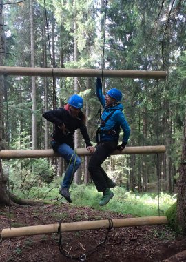 In unserem Wald-Seilgarten am Allgäuer Berghof eine wackelnde Leiter bezwingen, indem man seine eigene Balance und Stabilität sichert und gleichzeitig seinem Team hilft.