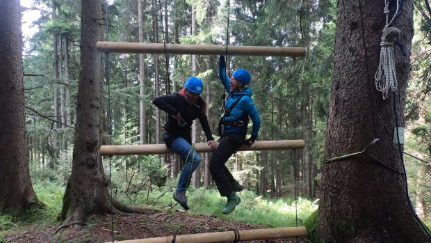 In unserem Wald-Seilgarten am Allgäuer Berghof eine wackelnde Leiter bezwingen, indem man seine eigene Balance und Stabilität sichert und gleichzeitig seinem Team hilft.