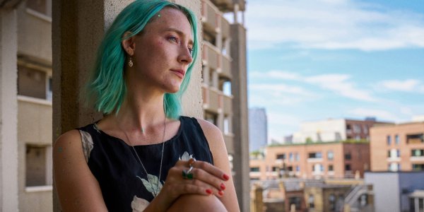 Szene aus dem Film: The Ortrun. Junge Frau mit grünen Haaren auf einem Balkon.