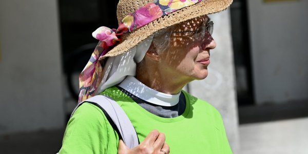 Schwester Helen begleitet die Pilgerwanderung und trägt einen bunten Sonnenhut zum grünen T-Shirt.