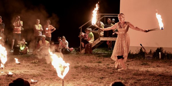 Eine Künstlerin führt faszinierende Feuerakrobatik bei der Pilgerwanderung vor.