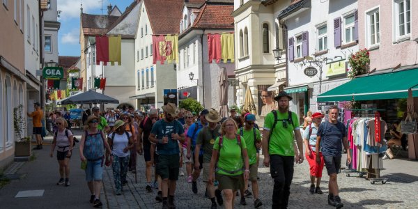 Die Gruppe von Wanderern spaziert in leuchtenden Shirts durch die sonnige Wassertorstraße.