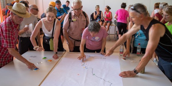 Die Pilger verewigen sich mit einem Fingerabdruck auf einem Plakat. Das Plakat zeigt den Routenverlauf der Pilgerwanderung.