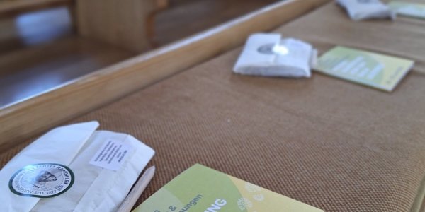 Auf den Bänken liegen Pilgerführer und kleine Kärtchen für die Wanderung nach Leichtkirch am 28. und 29. Juni 2023.