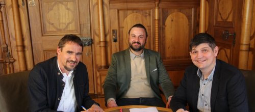Bürgermeister Rainer Magenreuter (von links), Benjamin Roll (GlasfaserPlus) und Daniel Weisshaar (Deutsche Telekom) bei der Unterzeichnung der gemeinsamen Erklärung zum Glasfaserausbau in Isny. Foto: Stadt Isny/Michael Panzram