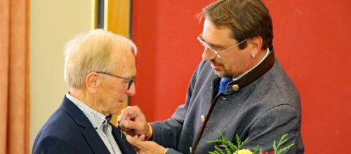 Bürgermeister Rainer Magenreuter steckt Hans Jäck die Ehrrennadel an. Foto: Stadt Isny/Michael Panzram