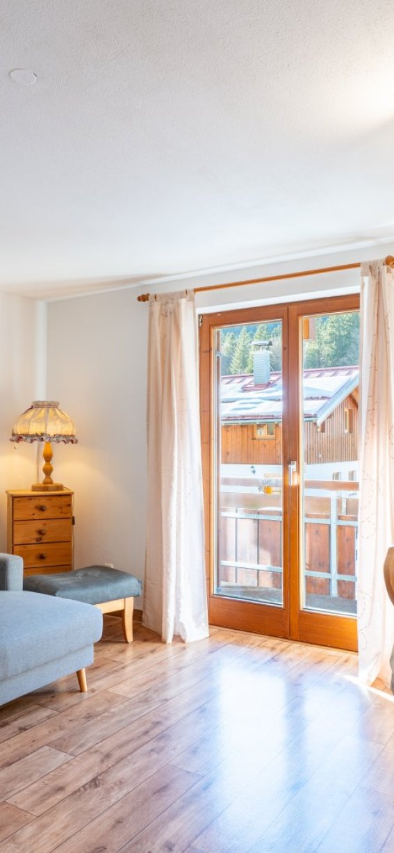Wohnzimmer in einer Wohnung in den Bergen Ein gemütliches Wohnzimmer in einer Wohnung in den Bergen. Es gibt ein Sofa, einen Tisch und einen Balkon mit Aussicht.