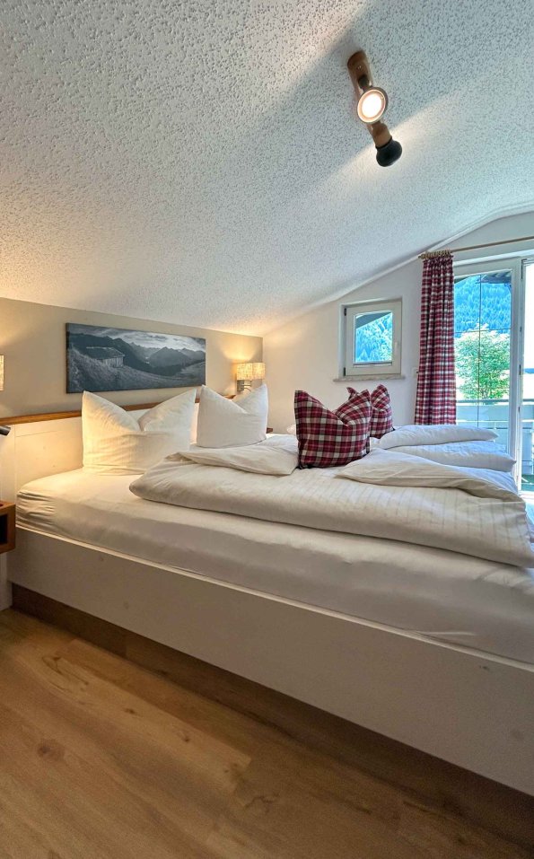 Das Zimmer hat zwei Betten und Fenster mit Blick auf die Berge. Es gibt Kissen auf dem Bett und eine freundliche Atmosphäre.