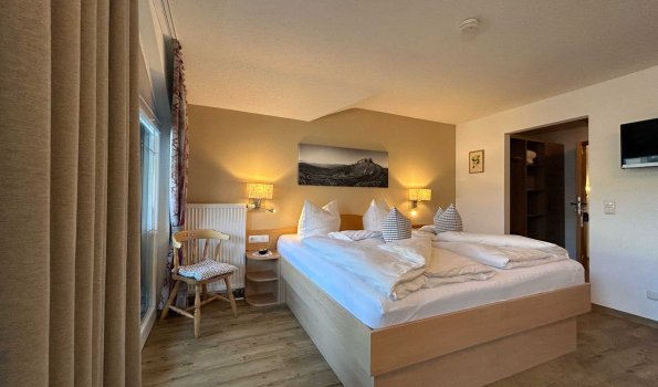 Schlafzimmer mit zwei Betten in einer Unterkunft In einem Zimmer stehen zwei Betten mit Kissen. Neben den Betten sind Lampen. Es gibt einen kleinen Tisch.