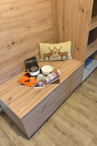Eine Holzbank steht in einem Raum. Auf der Bank liegen Bücher, eine Kerze und Dekoration.
