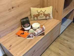 Eine Holzbank steht in einem Raum. Auf der Bank liegen Bücher, eine Kerze und Dekoration.