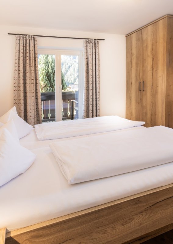 Es gibt ein Zimmer mit zwei Betten, einem Schreibtisch und einem Fernseher. Die Möbel sind aus Holz und das Zimmer ist hell.