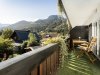 Balkon mit Blick auf Berge und Garten Ein Balkon zeigt einen schönen Blick auf Berge und Gärten. Der Himmel ist blau und die Pflanzen sind grün.
