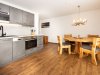 Küche und Essbereich in einem modernen Raum In diesem Raum befindet sich eine Küche und ein Essbereich mit einem Holztisch und Stühlen. Es ist hell und modern.