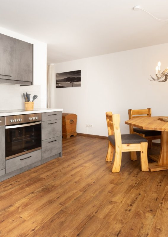 In diesem Raum befindet sich eine Küche und ein Essbereich mit einem Holztisch und Stühlen. Es ist hell und modern.