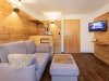 Moderne Wohnung mit Holzdesign und Fernseher In der Wohnung sind ein graues Sofa, ein Holztisch und ein Fernseher zu sehen. Der Raum hat Holzverkleidung und viel Licht.
