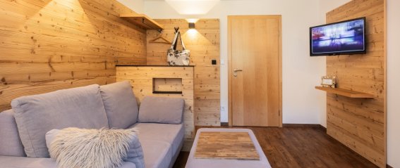 Moderne Wohnung mit Holzdesign und Fernseher In der Wohnung sind ein graues Sofa, ein Holztisch und ein Fernseher zu sehen. Der Raum hat Holzverkleidung und viel Licht.
