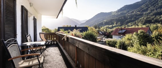 Balkon mit Blick auf die Berge in der Morgensonne Der Balkon hat Stühle und einen Tisch und bietet einen Blick auf die Berge. Es ist Morgen und die Sonne scheinen.