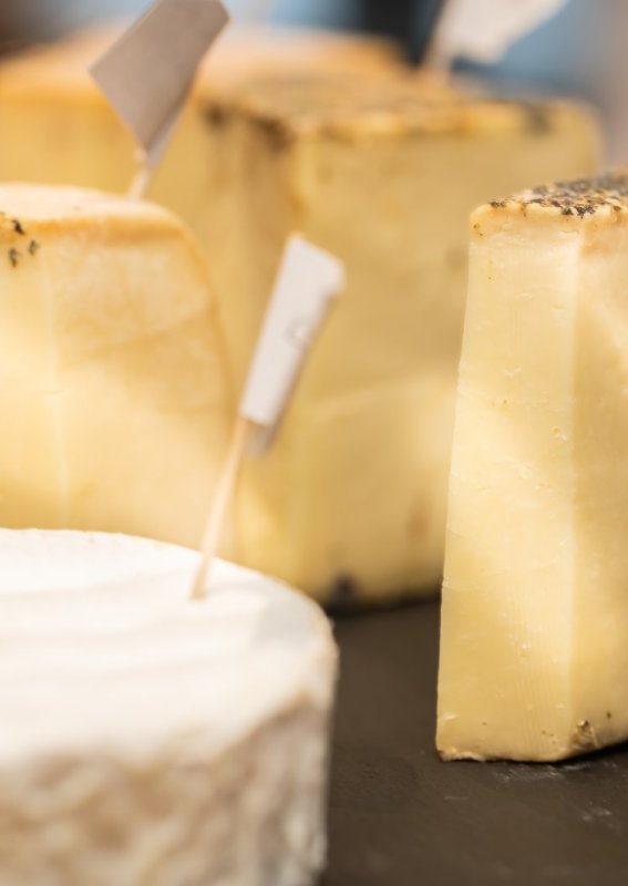 Auf einem Tisch stehen verschiedene Käsesorten und Trauben. Es gibt kleine Fähnchen zur Kennzeichnung der Käse.