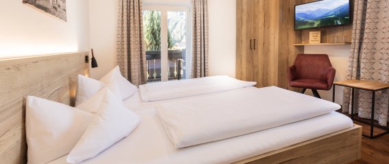 Doppelzimmer mit modernem Design und Aussicht In einem Hotelzimmer sind zwei Betten und ein Schreibtisch. Der Raum hat einfache Möbel und Fenster mit Aussicht.