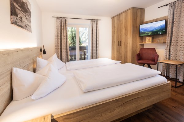 In einem Hotelzimmer sind zwei Betten und ein Schreibtisch. Der Raum hat einfache Möbel und Fenster mit Aussicht.