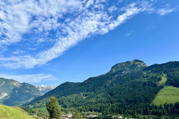 Eine Landschaft zeigt Berge, Gras und einen blauen Himmel mit Wolken. Diese Szene befindet sich in einer ruhigen Gegend.