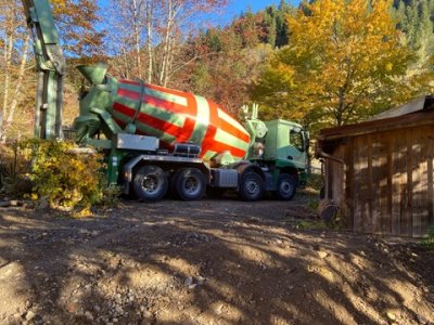 Ein Betonmischwagen steht in einer landschaftlichen Umgebung und bereit, frischen Beton zu liefern.
