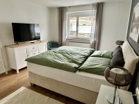 Das große Schlafzimmer mit Boxspringbett und großem Fernseher mit MagentaTV.