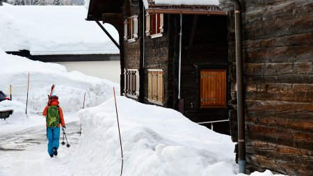 alte holzhaeuser, person mit ski aufderschulter,schneewand