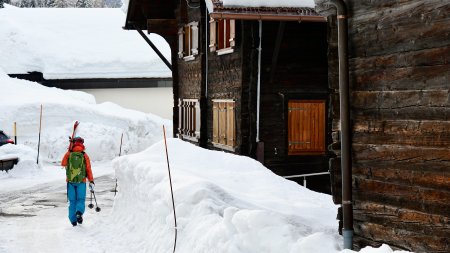 alte holzhaeuser, person mit ski aufderschulter,schneewand