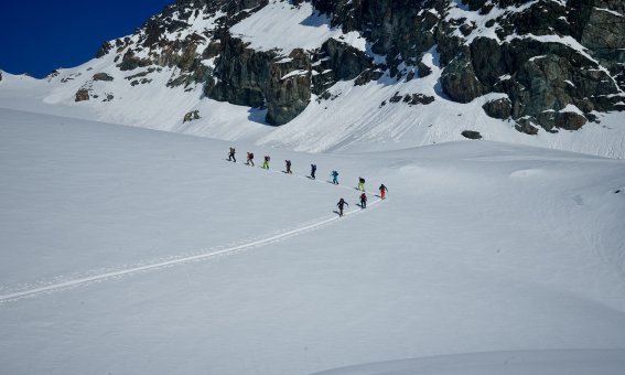 skitourengruppe, mehrer personen, skispur, schnee, felsen, blauer himmel